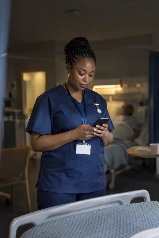 A staff nurse reading a short training lesson on her phone during a quiet moment on the ward